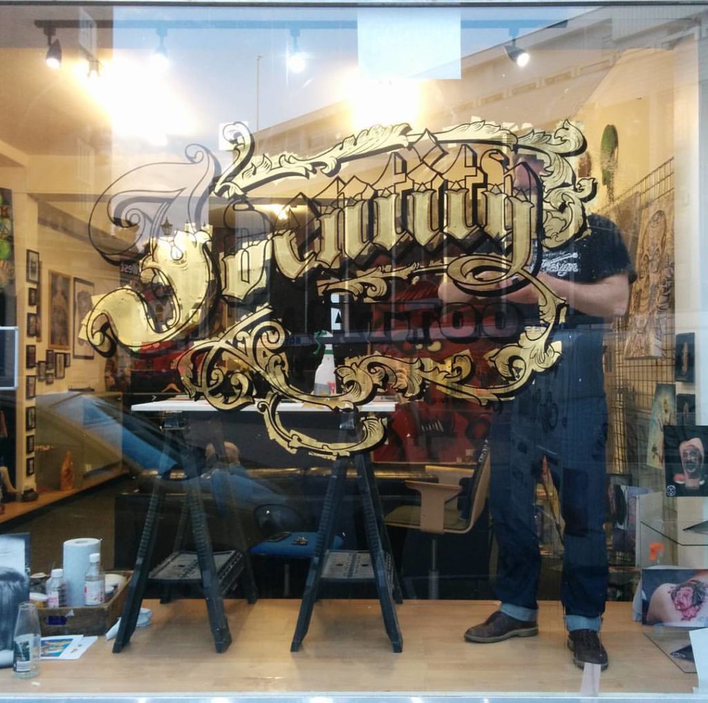 Sign Writer working on a tattoo studio gold leaf sign